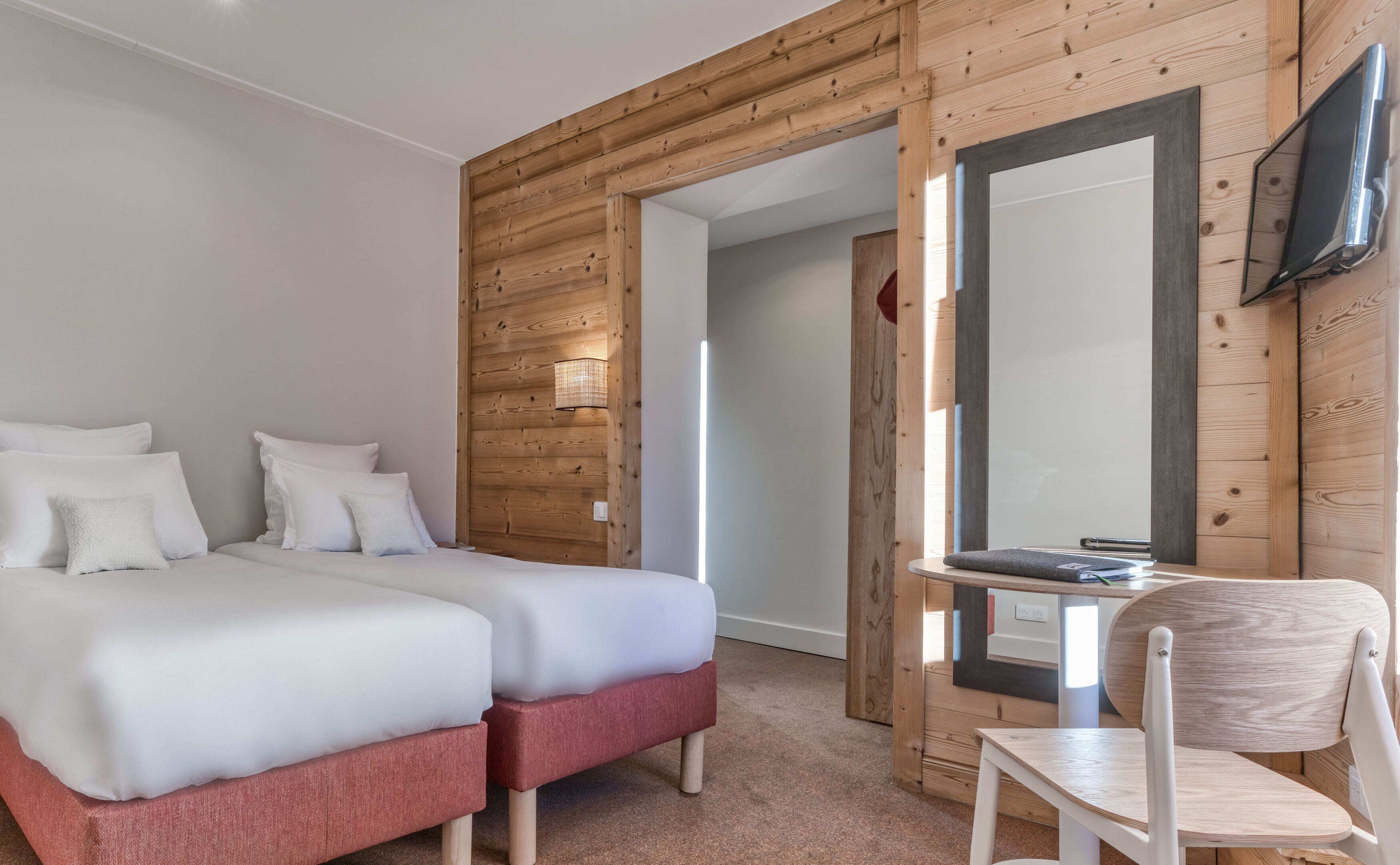 A bedroom with a double bed, a small desk with a chair, and a mirror.