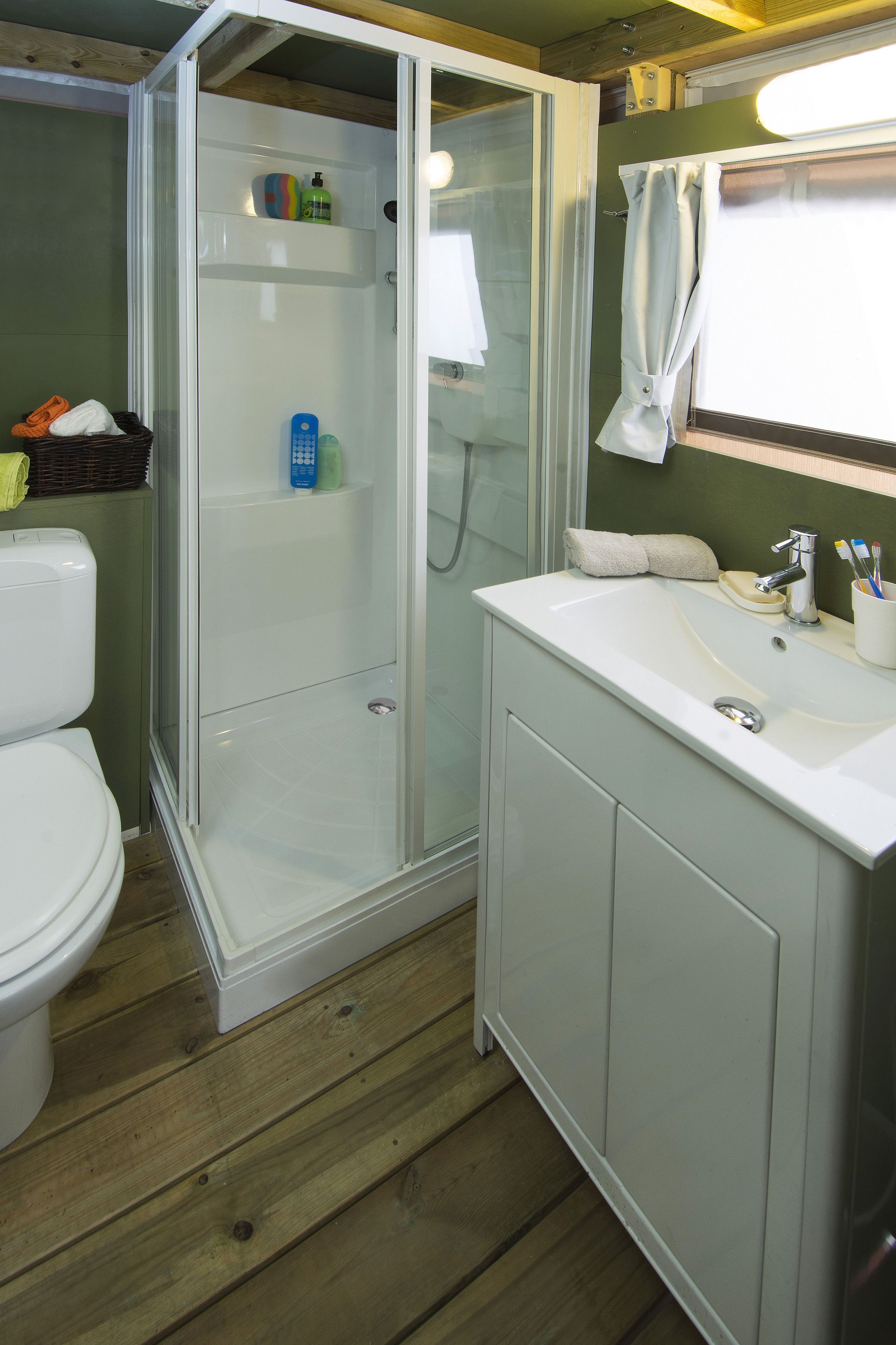 A bathroom with a glass-enclosed shower, a white sink with a mirror, and a toilet.