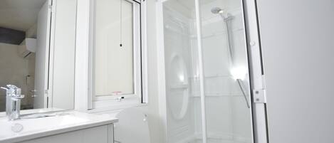 Un baño moderno con inodoro, lavabo y cabina de ducha de vidrio.