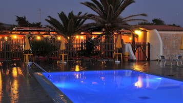 Una piscina al aire libre de temporada, sombrillas