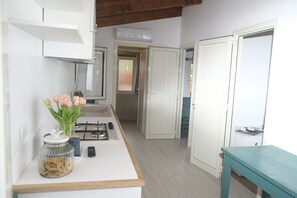 A kitchen with a white countertop, a gas stove, a jar of cookies, and a vase of tulips. - Torre del Porticciolo Camping Village Glamping (Alghero)