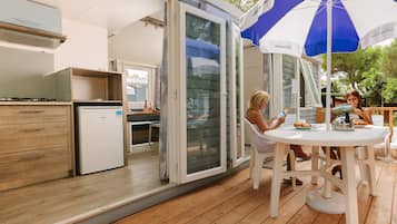 Compact living space with a kitchenette, sliding glass door to an outdoor area, and a dining table.