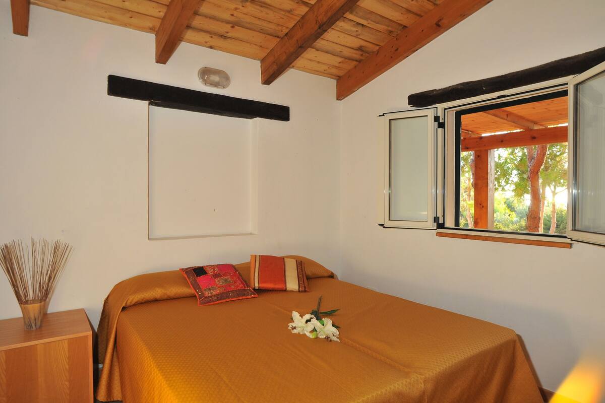 Un dormitorio con una cama, una ventana y techo de madera.