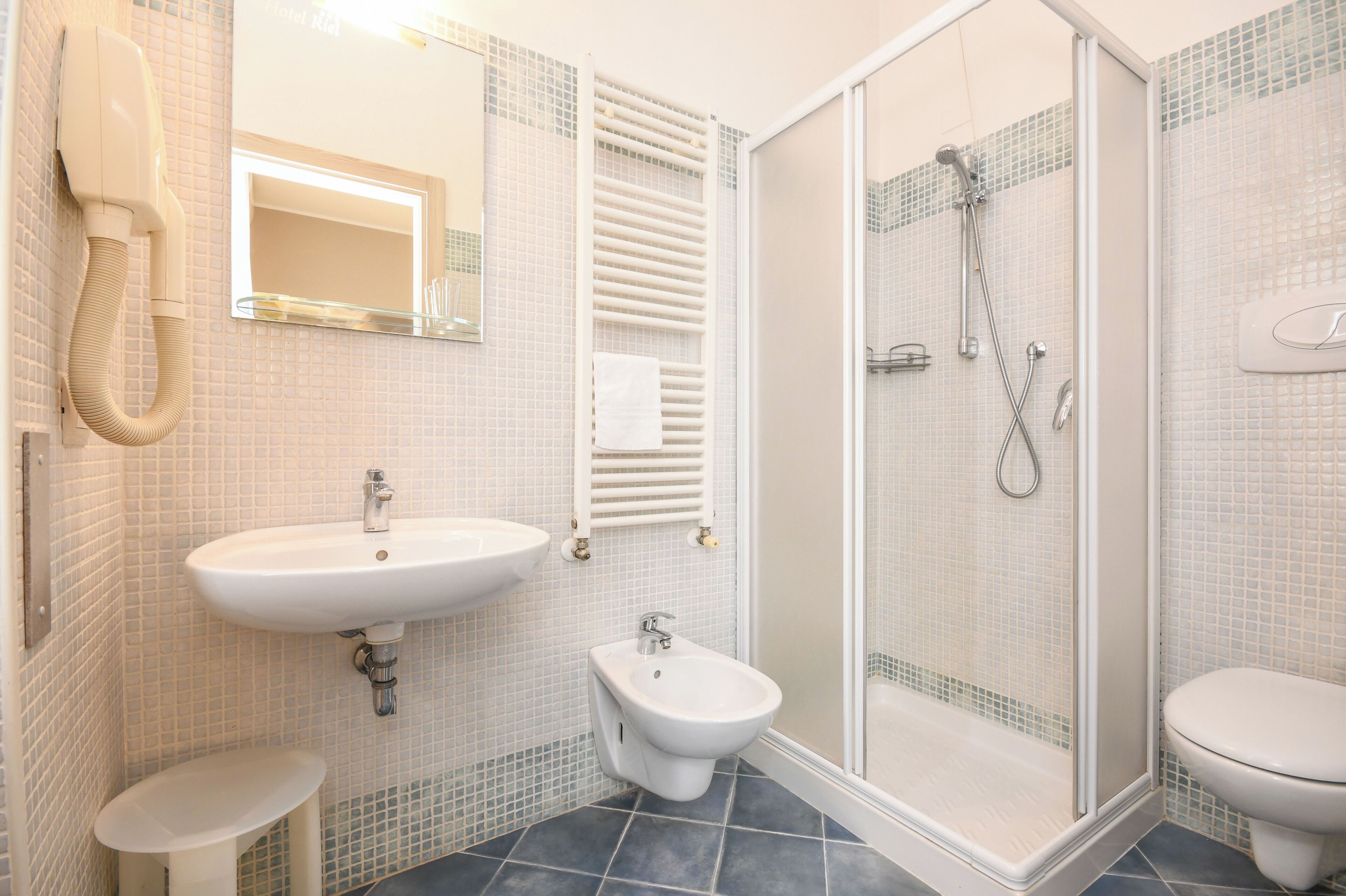 Un baño con lavabo, bidé, inodoro y cabina de ducha con mampara de vidrio.
