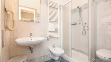 Un baño con lavabo, bidé, inodoro y cabina de ducha con mampara de vidrio.