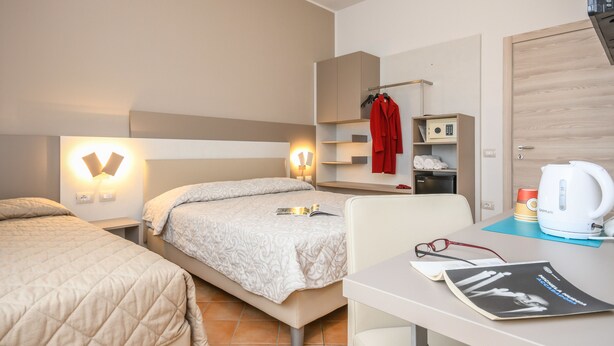 A hotel room with a bed, bedside tables, a desk with a kettle, and a wardrobe. - Hotel Riel (Sirmione)
