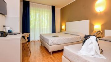 Habitación de hotel con una cama, un escritorio con una computadora y una silla.