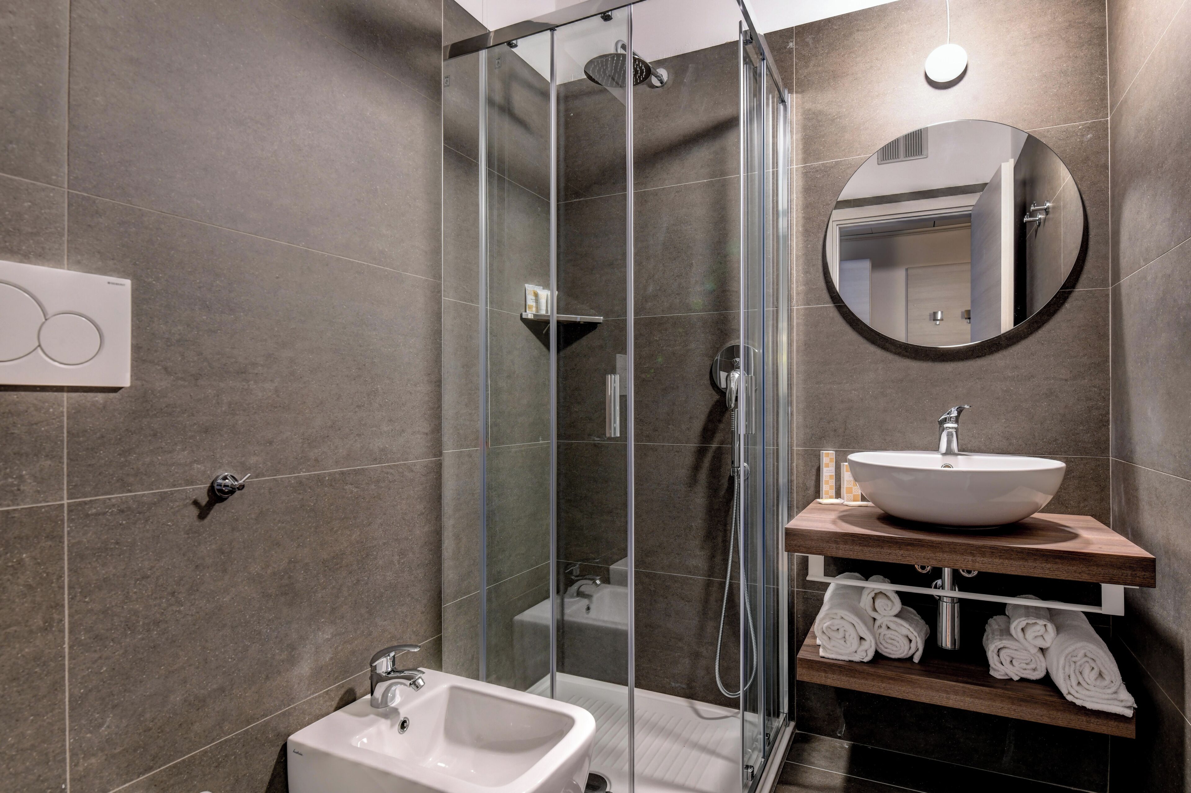 Un baño moderno con ducha acristalada, lavabo blanco y tocador de madera.