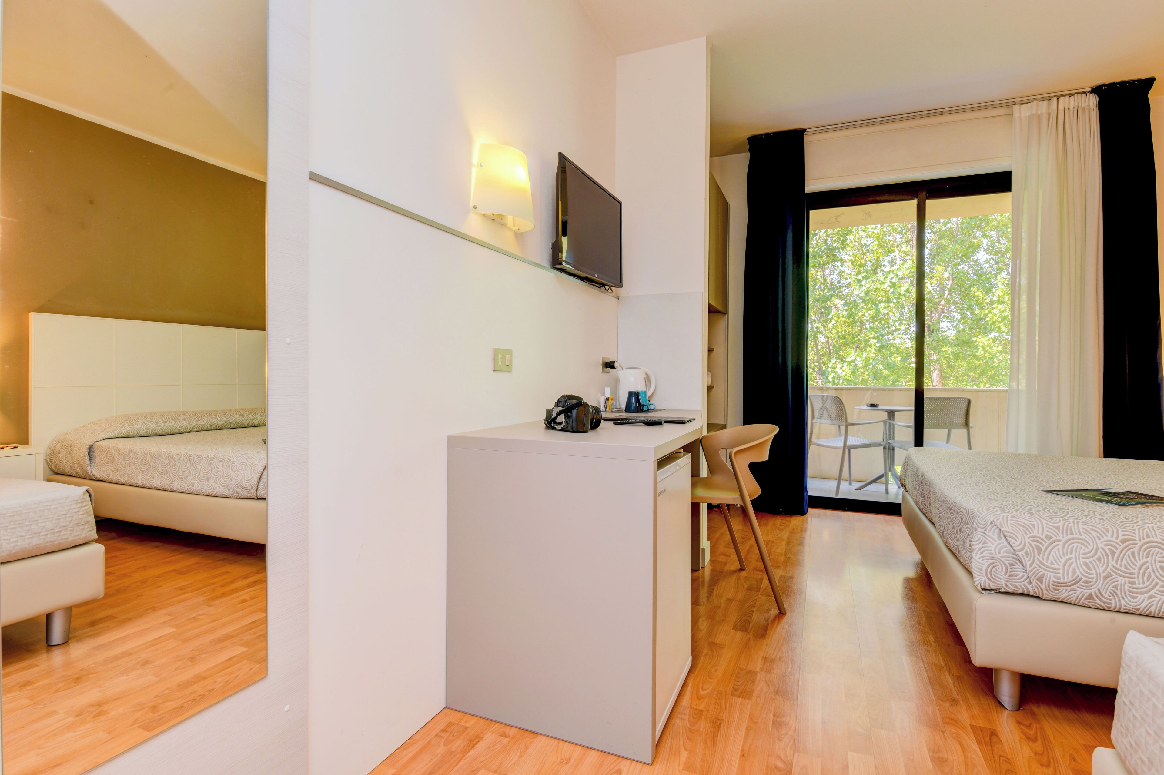 Une chambre d’hôtel avec deux lits, un bureau, une chaise, une télévision et une vue sur l’extérieur.