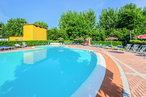 Una piscina amb una superfície d'aigua transparent i blava, envoltada de gandules i ombrelles.