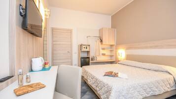Une chambre d’hôtel équipée d’un lit, d’un bureau, d’une chaise, d’une télévision, d’un coffre-fort et d’un mini-bar.