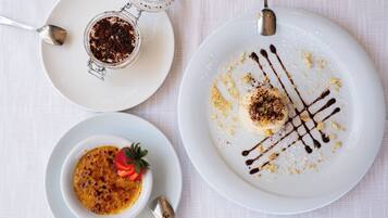 Three white plates with desserts on a white tablecloth.
