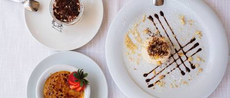 Three white plates with desserts on a white tablecloth.