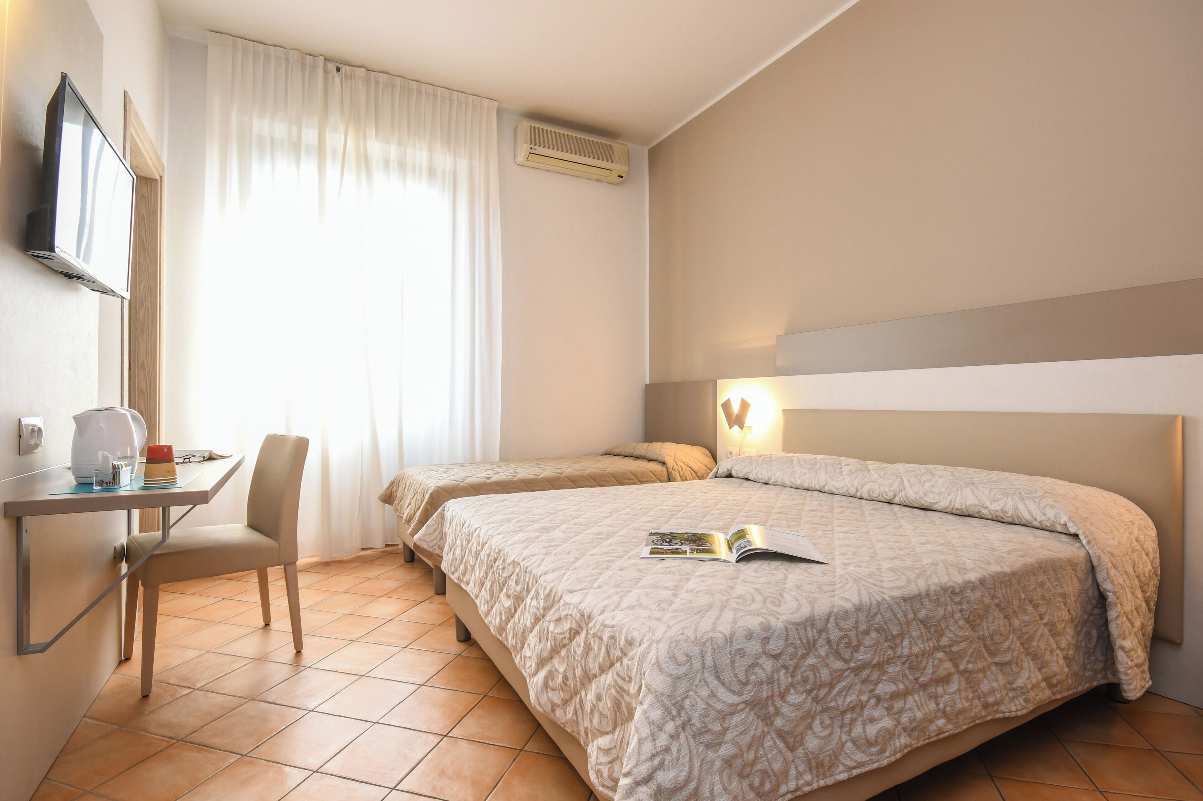 A hotel room with a bed, a desk, a chair, and a television.
