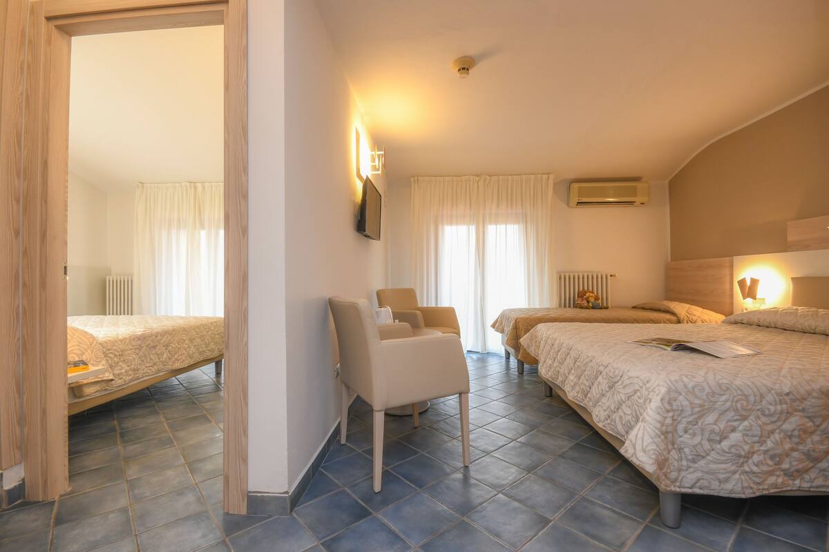 Habitación de hotel con dos camas, una silla, un televisor de pantalla plana y un radiador.