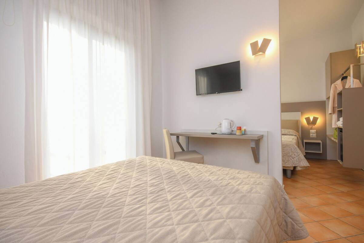 Una habitación de hotel con una cama, un escritorio, un televisor y un armario.