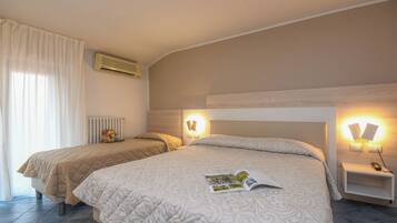 Habitación de hotel con dos camas, un radiador, aire acondicionado de pared y lámparas de noche.