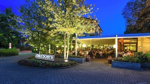 An outdoor seating area of a restaurant with a sign indicating it offers pizza.