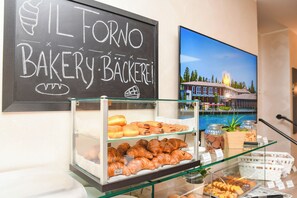 A bakery display with various baked goods and a chalkboard sign above it. - Hotel Riel (Sirmione)