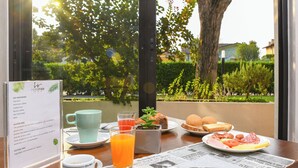 A breakfast table with a menu, a cup of coffee, a glass of orange juice, a plate of food, and a newspaper. - Hotel Riel (Sirmione)