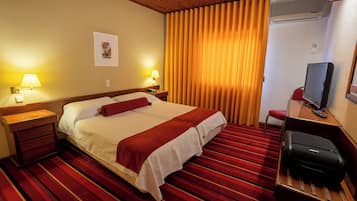 Habitación de hotel con una cama grande, dos lámparas de noche, un televisor y un escritorio con una silla.