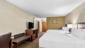 A hotel room with a bed, a desk with a television, a chair, and a door.