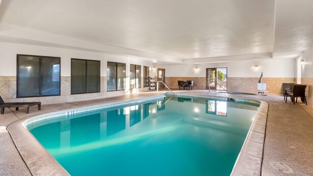 An indoor swimming pool with clear water, a tiled floor, and a seating area with chairs and tables. - Comfort Inn & Suites Thatcher - Safford (Thatcher)