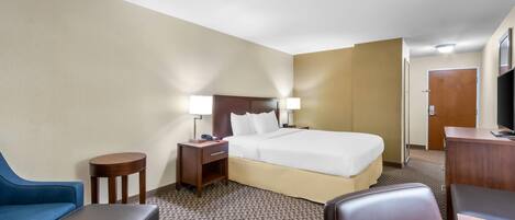A hotel room with a bed, two bedside tables, a desk, a chair, and a blue sofa.