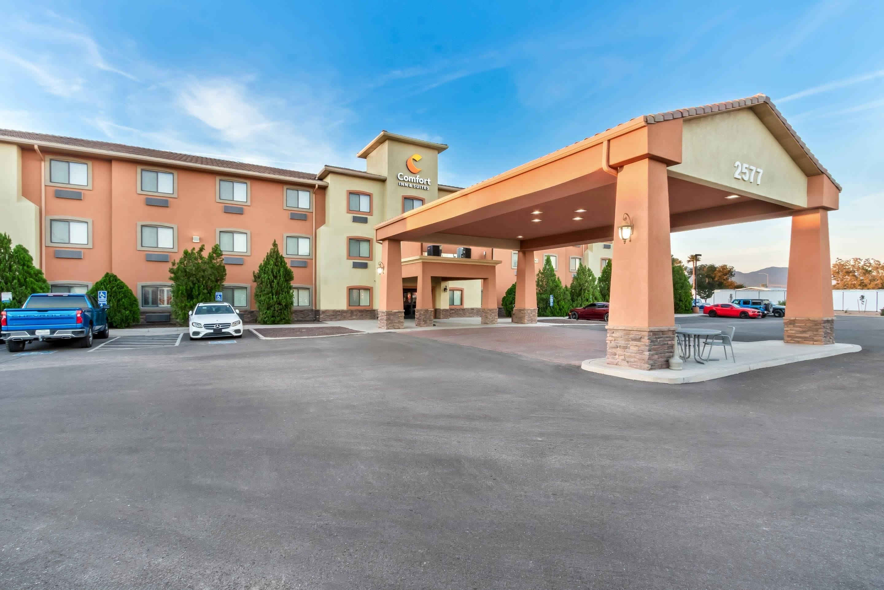 A hotel with a covered entrance, multiple parking spaces, and a clear sky.