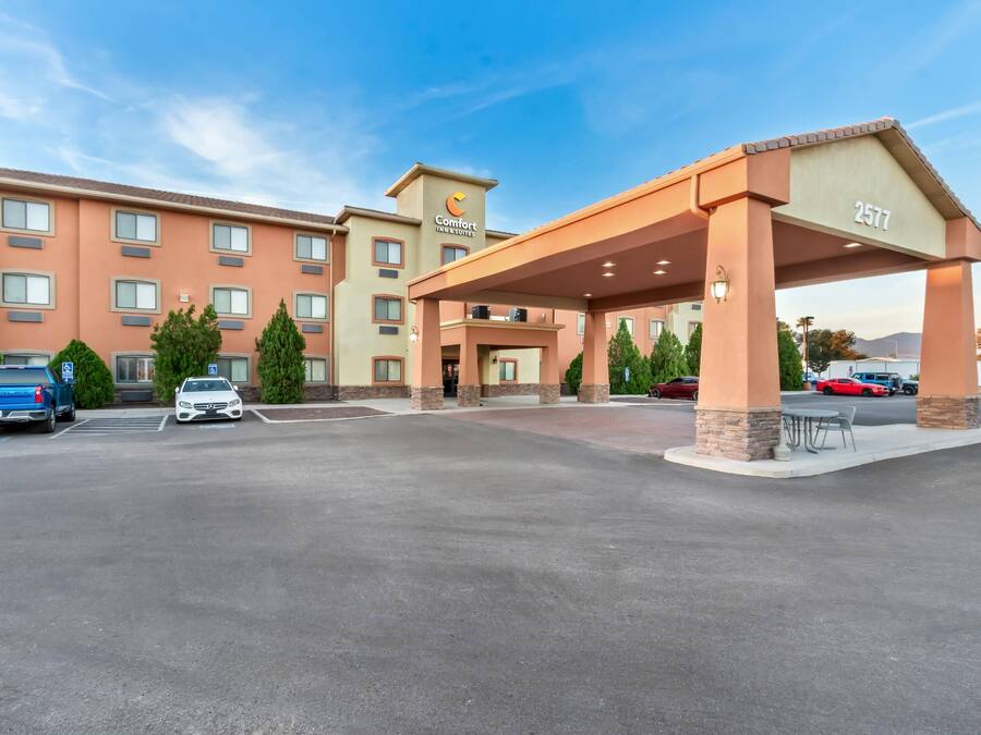 A hotel with a covered entrance, multiple parking spaces, and a clear sky.