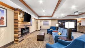 A modern lounge area with a fireplace, blue seating, and a flat-screen TV. - Comfort Inn & Suites Thatcher - Safford (Thatcher)