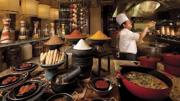Un chef dans une cuisine professionnelle, entouré de divers ustensiles de cuisine, de casseroles et d’épices.