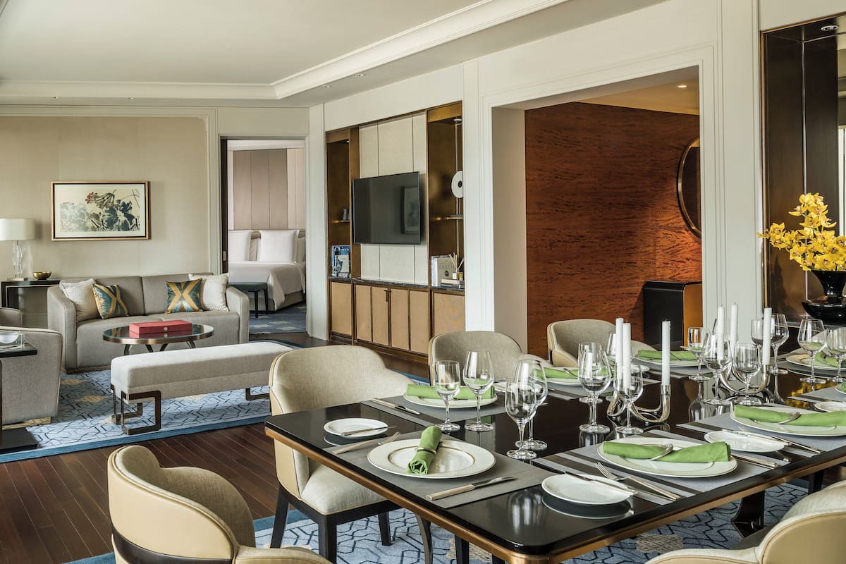 Une chambre d’hôtel moderne équipée d’un coin repas, d’un canapé, d’une télévision et d’un grand miroir.