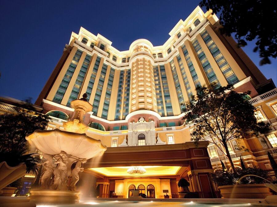 Un grande hotel a più piani con un ingresso imponente, una fontana e una statua.