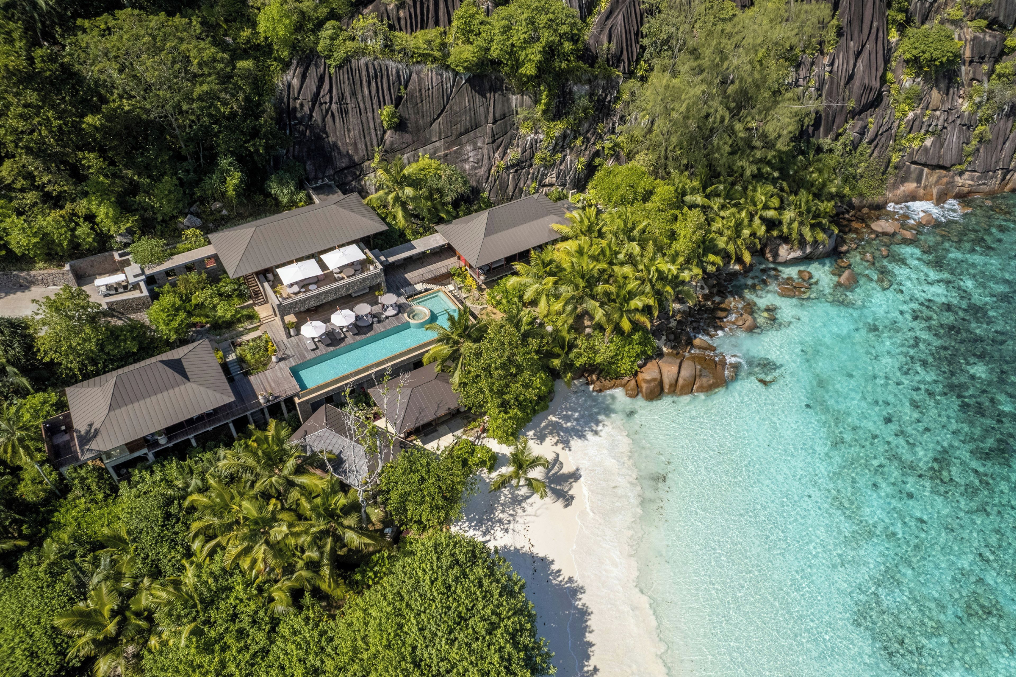 Vue aérienne d’un complexe hôtelier comprenant plusieurs bâtiments, une piscine et une plage.
