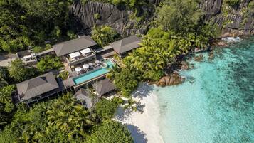 Vue aérienne d’un complexe hôtelier comprenant plusieurs bâtiments, une piscine et une plage.