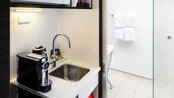 Una cocina moderna con microondas, cafetera y zona de ducha con paredes de vidrio.