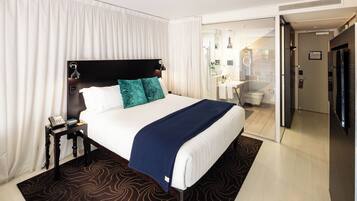 A hotel room with a large bed, a bedside telephone, and a bathroom visible through an open door.