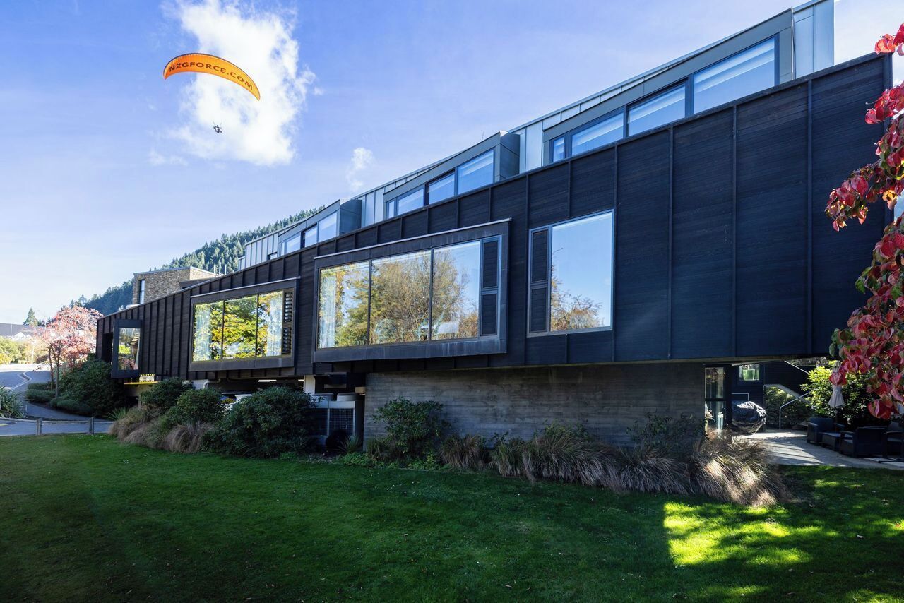 A modern building with large windows and a grassy area in front.