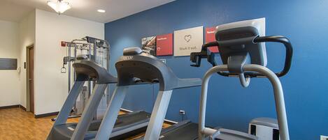 A gym with treadmills, a weight machine, and a wall with motivational posters.
