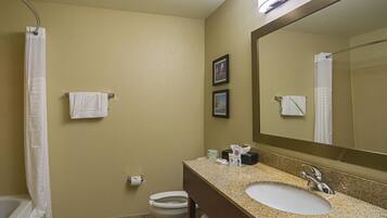A bathroom with a sink, mirror, toilet, and shower curtain.
