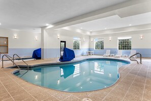 An indoor swimming pool with clear water, tiled floor, and walls, surrounded by lounge chairs and a covered bench. - Comfort Suites Grayslake near Libertyville North (Grayslake)