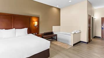 A hotel room with a large bed, a bench, a bathtub, and a desk.