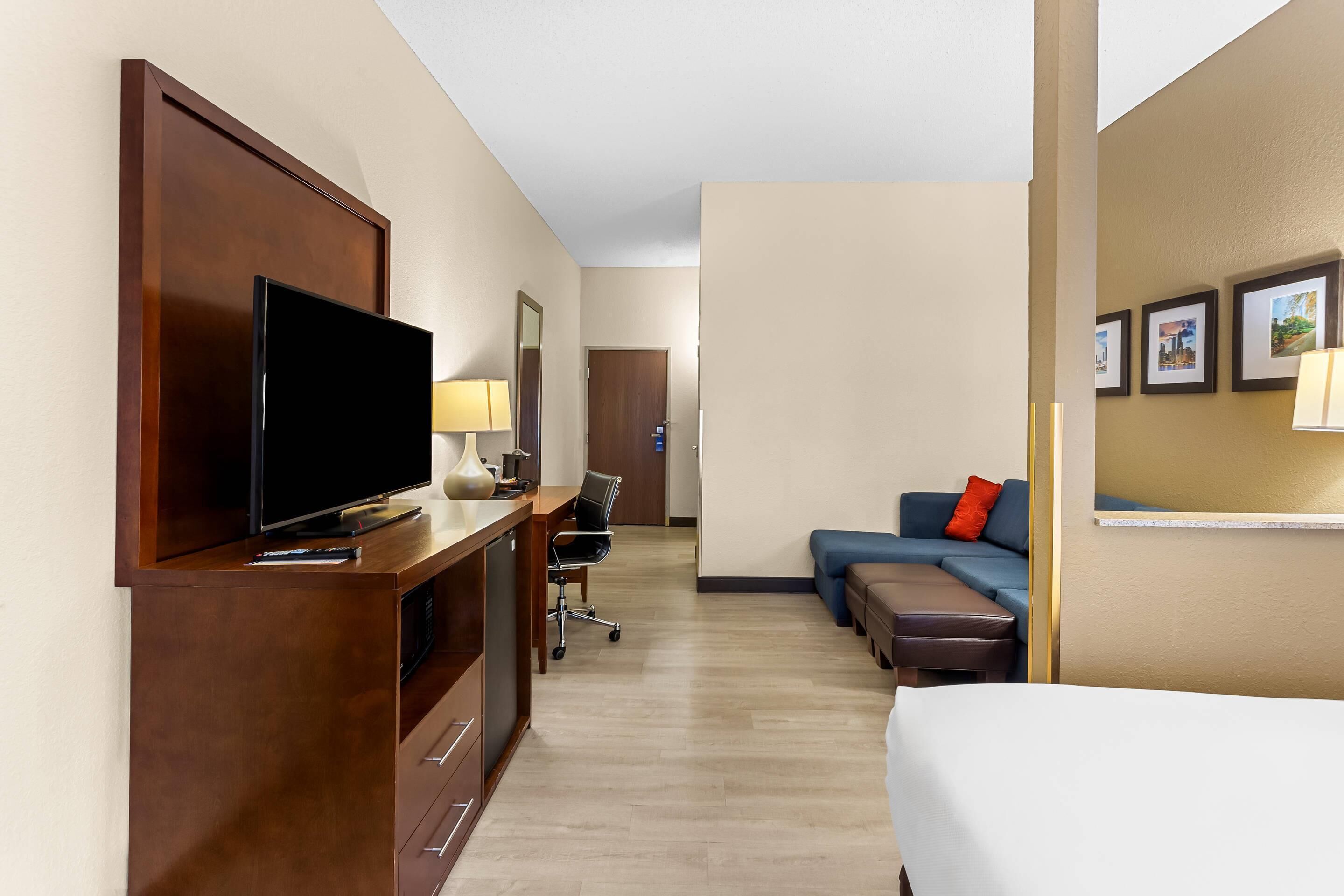 Habitación de hotel con televisión, escritorio, silla, sofá y cama.