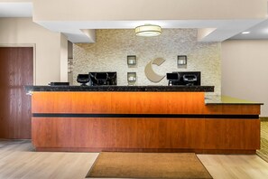 Un mostrador de recepción con detalles de madera, una pared de piedra con un diseño de luna creciente grande y un accesorio de iluminación moderno en el techo.