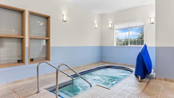 Uma área de spa com hidromassagem, uma janela com persianas e uma toalha azul em um suporte.