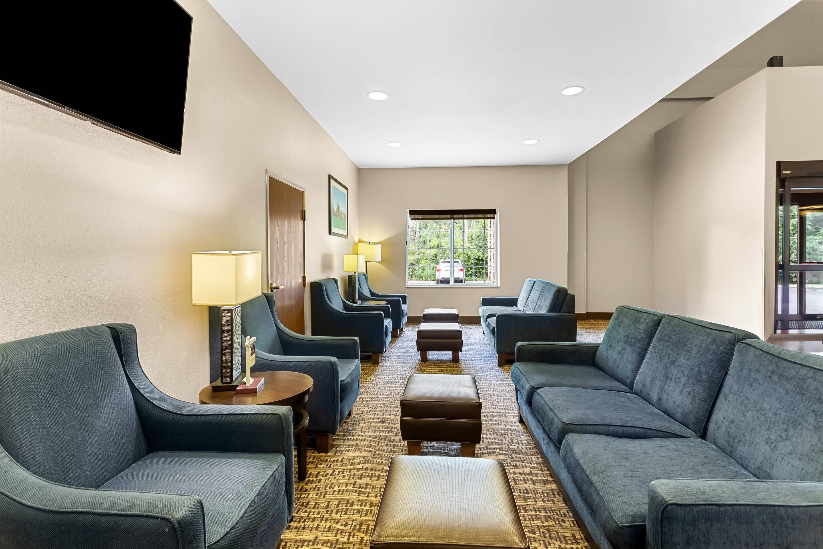 A hotel lobby with sofas, lamps, a TV, and a window with a view.