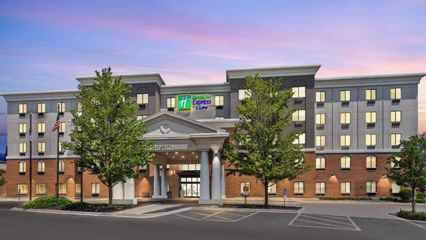 A multi-story hotel with a central entrance, a flag, and a sign for Express Suites.