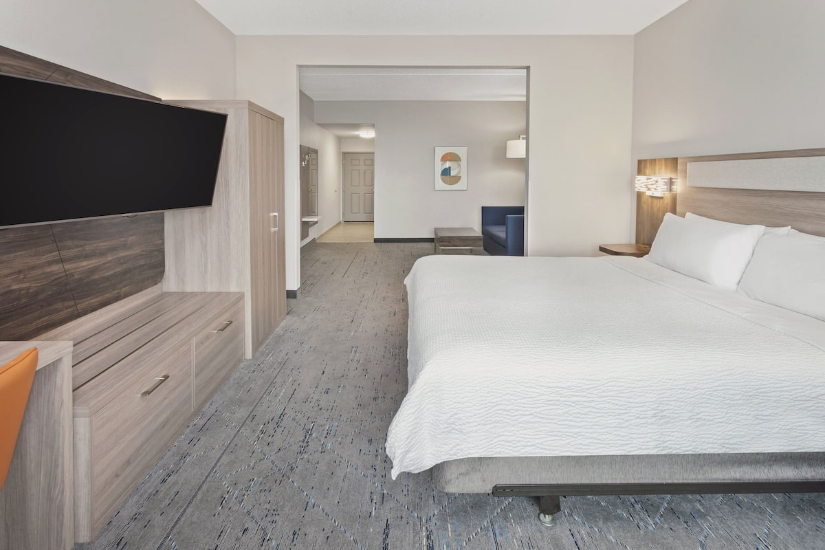 A hotel room with a large bed, a flat-screen TV mounted on the wall, a desk, and a chair.
