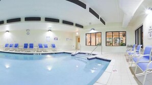 An indoor swimming pool with blue chairs and a tiled floor.